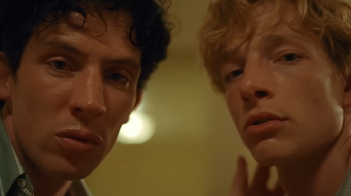 Josh O'Connor and Mike Faist in a dimly lit room with intense expressions on a scene from movie 'Challengers'. Josh O'Connor and Mike Faist in a dimly lit room with intense expressions on a scene from movie 'Challengers'.