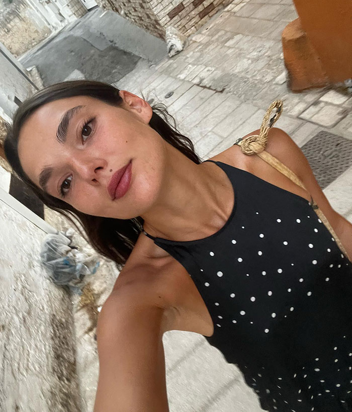 Young woman taking a selfie in a black polka dot top, outdoors on a cobblestone street. Young woman taking a selfie in a black polka dot top, outdoors on a cobblestone street.