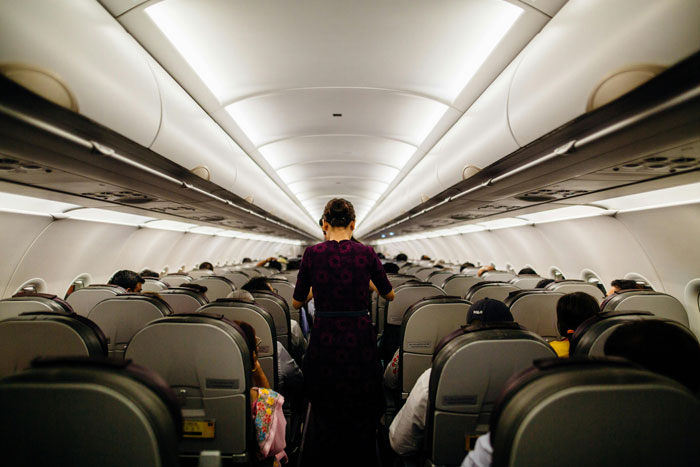 Flight attendant walking down aircraft aisle, addressing seat arrangement and mobility issues. Flight attendant walking down aircraft aisle, addressing seat arrangement and mobility issues.