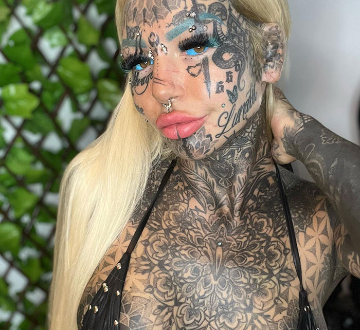 Australia's most tattooed woman posing, showcasing extensive ink designs on her face and body. Australia's most tattooed woman posing, showcasing extensive ink designs on her face and body.