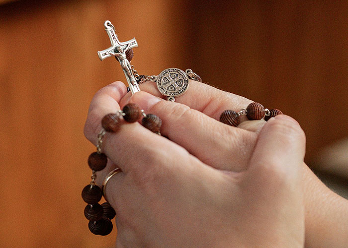 Hands holding a rosary, symbolizing contemplation or prayer, related to a wedding date change. Hands holding a rosary, symbolizing contemplation or prayer, related to a wedding date change.