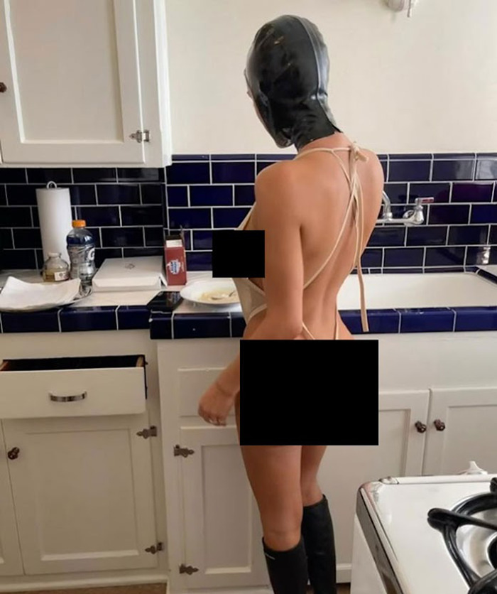 Bianca Censori in a kitchen wearing minimal clothing and a black head covering, standing by a counter. Bianca Censori in a kitchen wearing minimal clothing and a black head covering, standing by a counter.