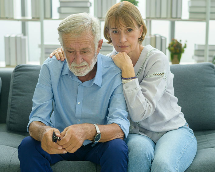 Older couple considering family tradition, looking contemplative on a couch. Older couple considering family tradition, looking contemplative on a couch.