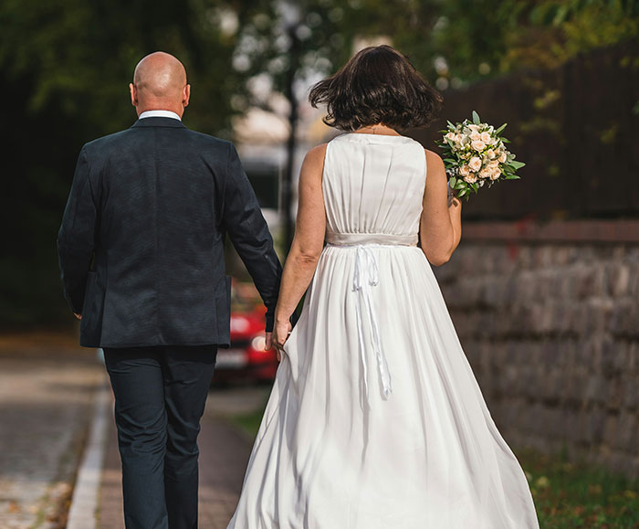 Bride and groom walking hand-in-hand outdoors, bride holding a bouquet, in a child-free wedding setting. Bride and groom walking hand-in-hand outdoors, bride holding a bouquet, in a child-free wedding setting.