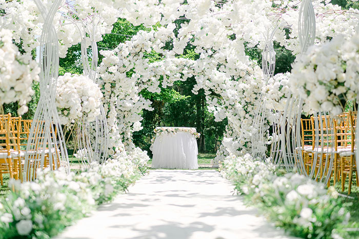 Wedding ceremony setup with floral archways and white flower decorations. Wedding ceremony setup with floral archways and white flower decorations.