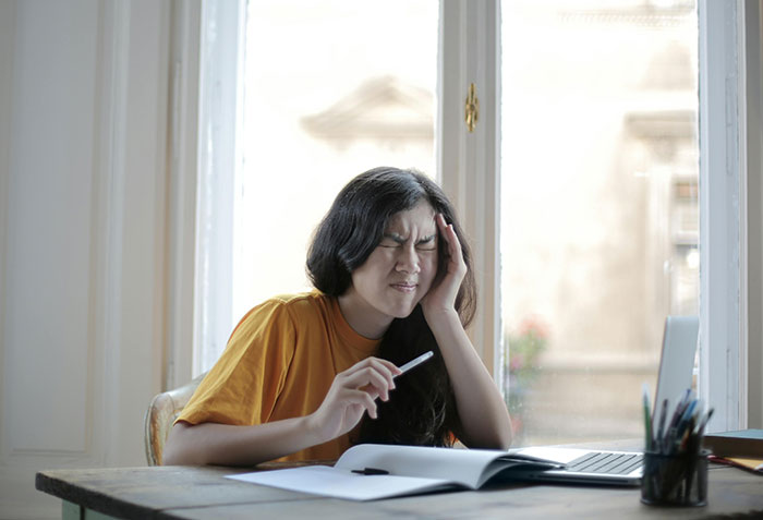 Woman in orange shirt stressed over wedding chores at desk with laptop and notebook. Woman in orange shirt stressed over wedding chores at desk with laptop and notebook.