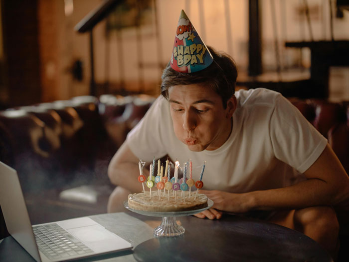 Young man at a birthday party blowing out candles on a cake, wearing a party hat. Young man at a birthday party blowing out candles on a cake, wearing a party hat.