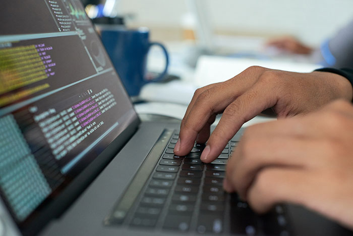 A man types on a laptop, coding with focus, possibly symbolizing frustration over Wi-Fi issues. A man types on a laptop, coding with focus, possibly symbolizing frustration over Wi-Fi issues.