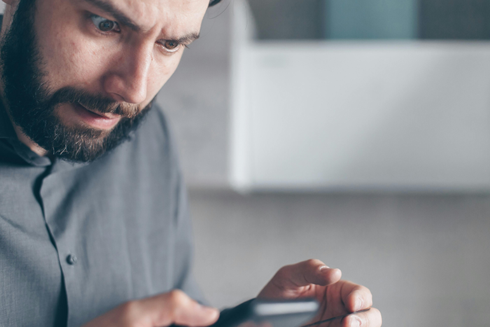 Man looking concerned at phone, relating to Bumble date and feeling 'stranded' scenario. Man looking concerned at phone, relating to Bumble date and feeling 'stranded' scenario.