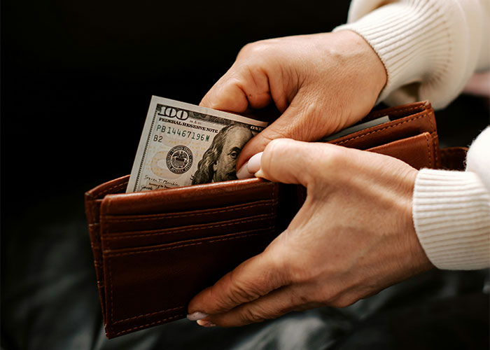 Hands holding a wallet with cash, representing employer demands for overpayment retrieval. Hands holding a wallet with cash, representing employer demands for overpayment retrieval.