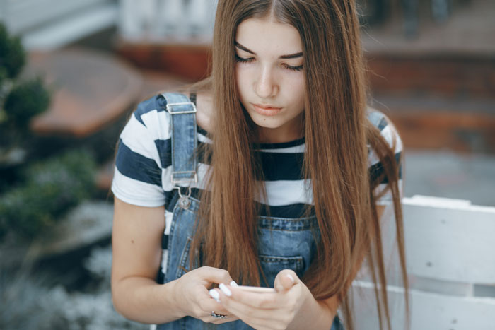 Young woman in overalls, checking her phone, looking pensive. Young woman in overalls, checking her phone, looking pensive.