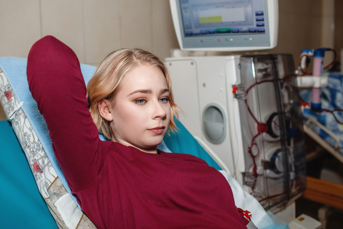 A woman in a hospital setting, reclining beside medical equipment, relating to an ex-friend's brother in care. A woman in a hospital setting, reclining beside medical equipment, relating to an ex-friend's brother in care.