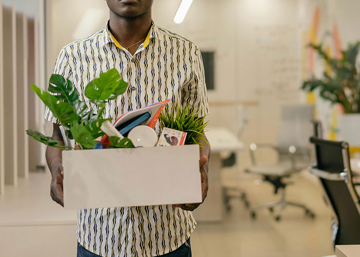 A person in an office holding a box of personal items, symbolizing CEO fails and management challenges.