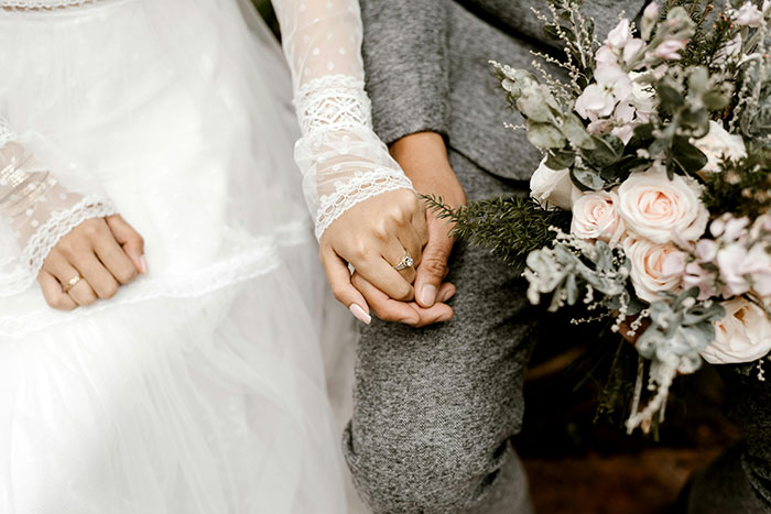 A couple holding hands, dressed in wedding attire, with a bouquet of flowers. A couple holding hands, dressed in wedding attire, with a bouquet of flowers.