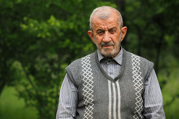 Elderly man outdoors in a patterned vest, representing a terrible father figure narrative. Elderly man outdoors in a patterned vest, representing a terrible father figure narrative.