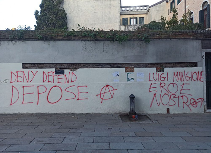 Graffiti on a wall referencing Luigi Mangione, with phrases in red paint, against an urban background. Graffiti on a wall referencing Luigi Mangione, with phrases in red paint, against an urban background.