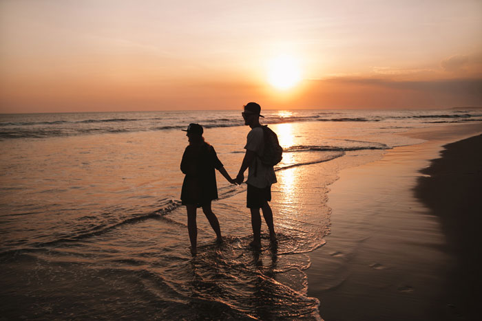 Couple walking on the beach at sunset, holding hands. Couple walking on the beach at sunset, holding hands.