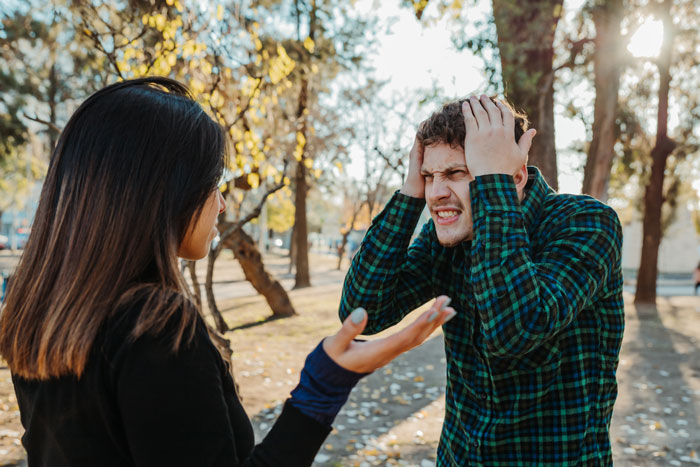 A man in a plaid shirt looking frustrated, holding his head, during a proposal rejection conversation in a park. A man in a plaid shirt looking frustrated, holding his head, during a proposal rejection conversation in a park.