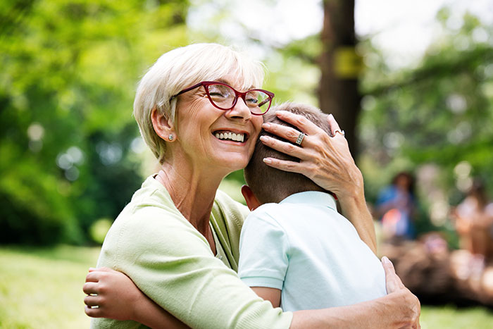 Grandma hugs boy in park, smiling courageously, preventing bullying incident. Grandma hugs boy in park, smiling courageously, preventing bullying incident.