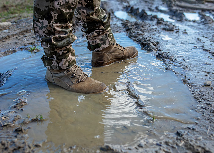 Camo pants and boots standing in a muddy puddle, representing water revenge. Camo pants and boots standing in a muddy puddle, representing water revenge.
