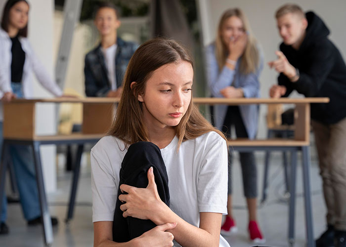A girl looking upset while three friends laugh and point, illustrating a prank at camp. A girl looking upset while three friends laugh and point, illustrating a prank at camp.