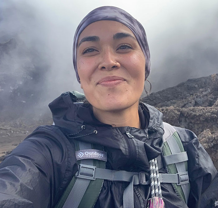 Woman hiking in rugged terrain, wearing outdoor gear, linked to green card marriage scam. Woman hiking in rugged terrain, wearing outdoor gear, linked to green card marriage scam.