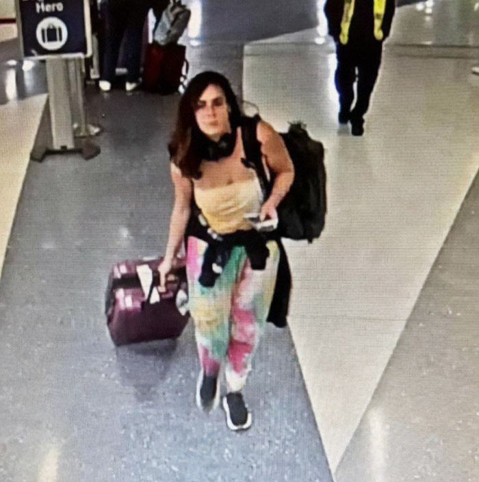 Woman at airport linked to green card marriage scam, carrying a suitcase and wearing colorful pants. Woman at airport linked to green card marriage scam, carrying a suitcase and wearing colorful pants.