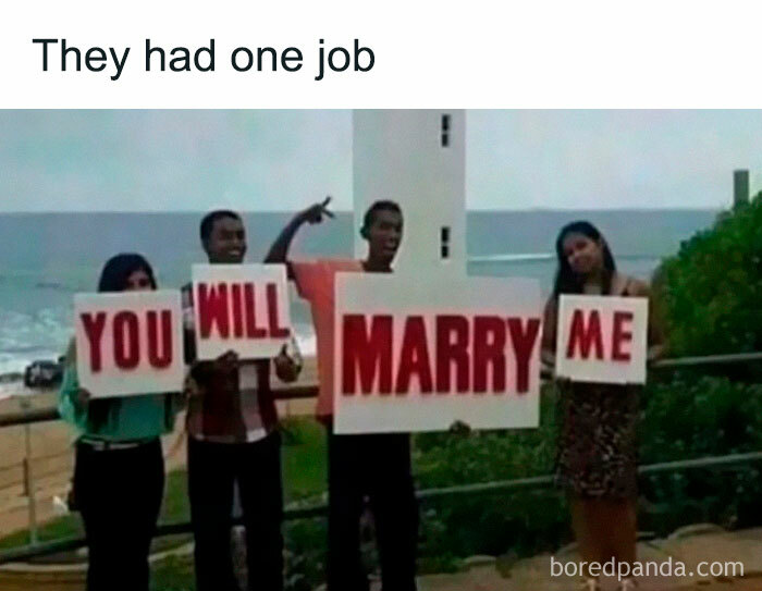 People holding signs that read "YOU MARRY WILL ME" on a beach, showcasing a funny fail moment.