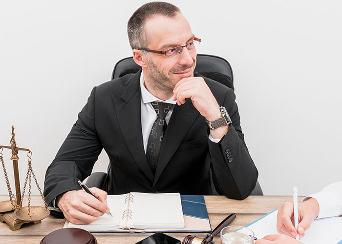 Man in a suit at a desk, taking notes, with scales of justice; concept of HOA fake violations. Man in a suit at a desk, taking notes, with scales of justice; concept of HOA fake violations.