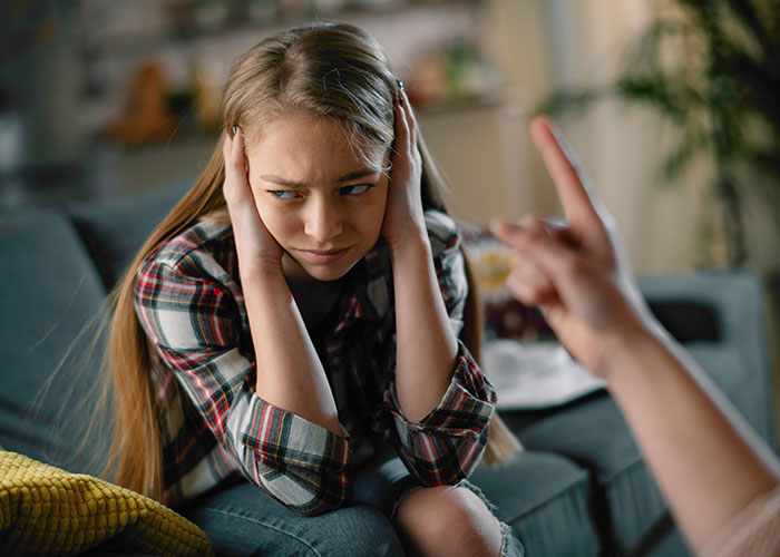 Teen girl covering ears during a discussion about her behavior towards baby. Teen girl covering ears during a discussion about her behavior towards baby.