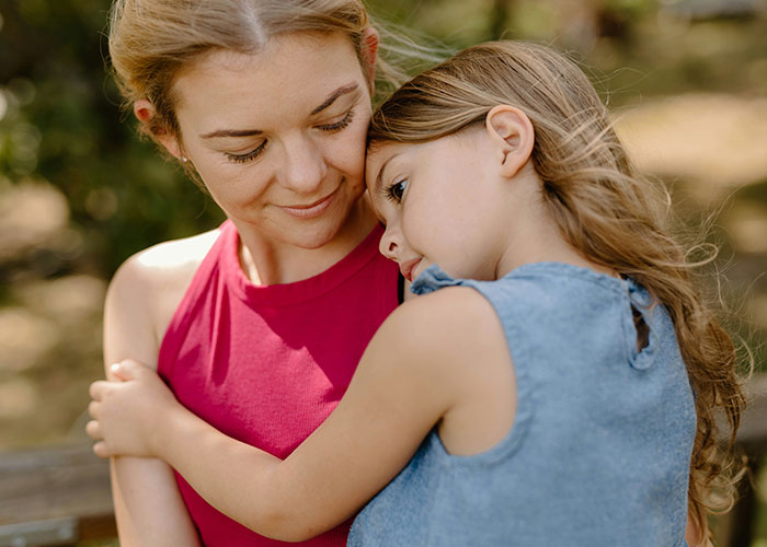 Mom contemplating marriage due to stepdaughter's emotions, comforting her in an outdoor setting. Mom contemplating marriage due to stepdaughter's emotions, comforting her in an outdoor setting.