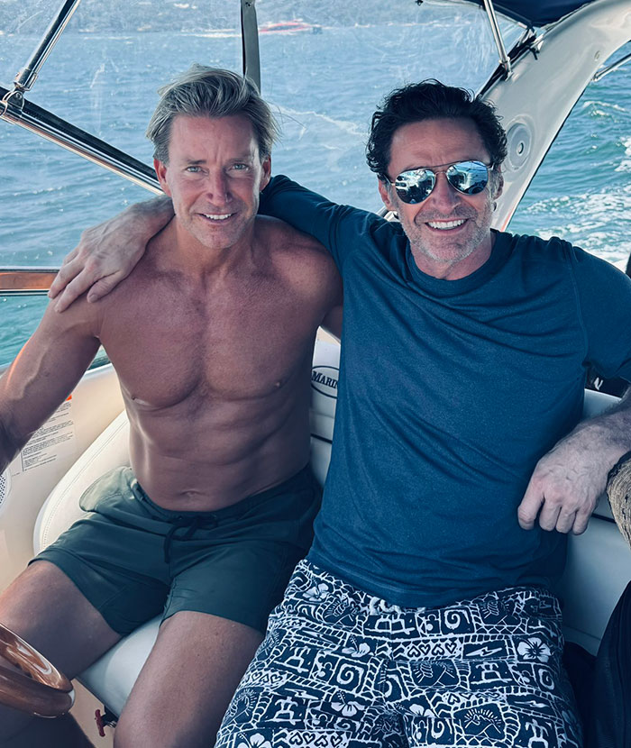 Two men on a boat smiling; rumors spark about Hugh Jackman with unknown figures. Two men on a boat smiling; rumors spark about Hugh Jackman with unknown figures.