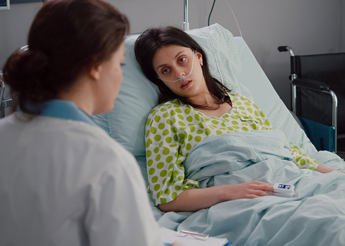 Woman in hospital bed with doctor, discussing surgery while using an oxygen tube, highlighting a husband's defensive absence. Woman in hospital bed with doctor, discussing surgery while using an oxygen tube, highlighting a husband's defensive absence.
