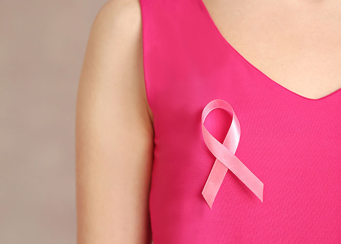 Person in a pink shirt wearing a breast cancer awareness ribbon. Person in a pink shirt wearing a breast cancer awareness ribbon.
