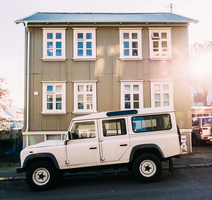 White SUV parked illegally near a residential building, sunlight gleaming on windows. White SUV parked illegally near a residential building, sunlight gleaming on windows.