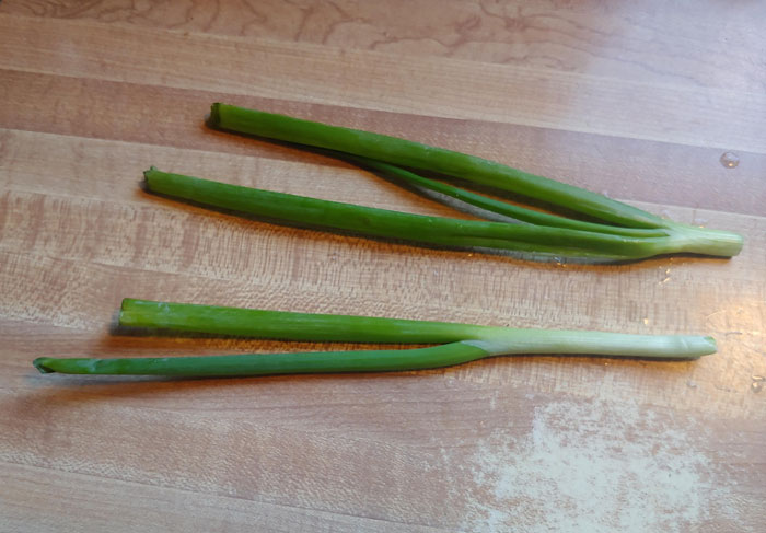 Two partially peeled leeks on a wooden surface, potentially frustrating for family members.