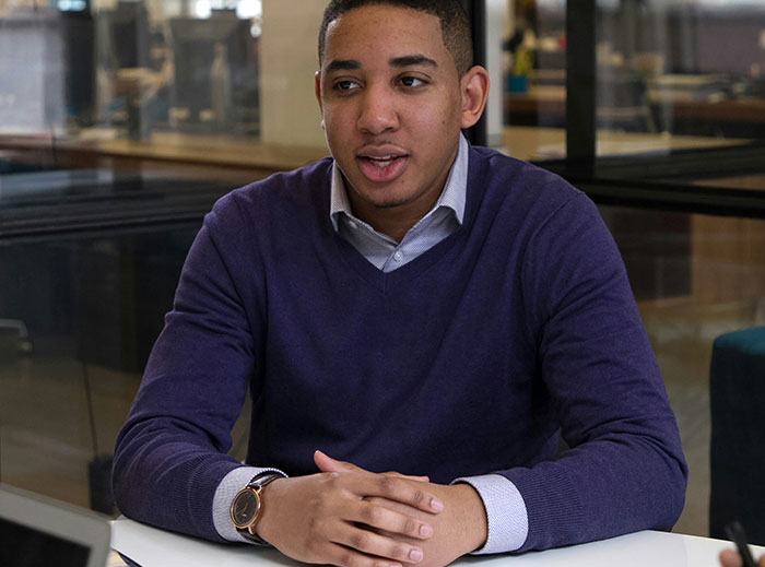 Candidate at job interview, seated, wearing a purple sweater, with a serious expression related to salary expectations. Candidate at job interview, seated, wearing a purple sweater, with a serious expression related to salary expectations.