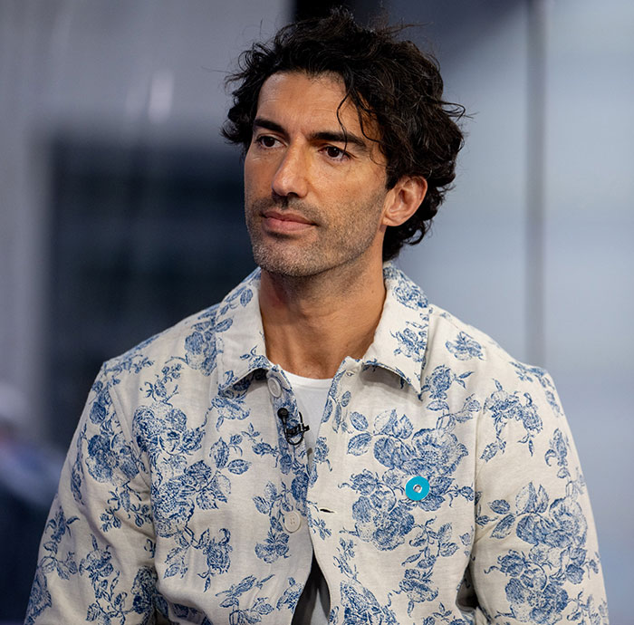 Man in a floral shirt appears thoughtful while sitting during an interview, focused on lawyer claims related to Justin Baldoni. Man in a floral shirt appears thoughtful while sitting during an interview, focused on lawyer claims related to Justin Baldoni.