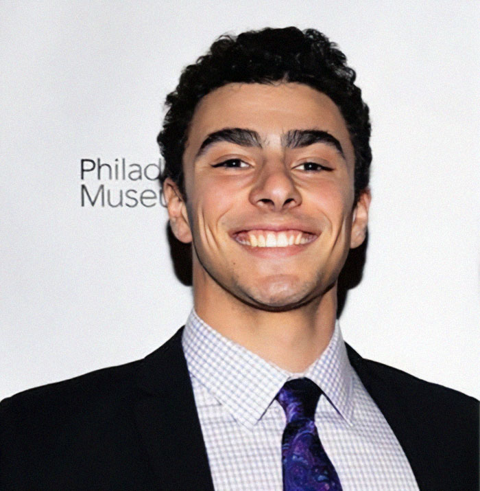 Luigi Mangione in formal attire at an event, with a backdrop featuring museum branding. Luigi Mangione in formal attire at an event, with a backdrop featuring museum branding.