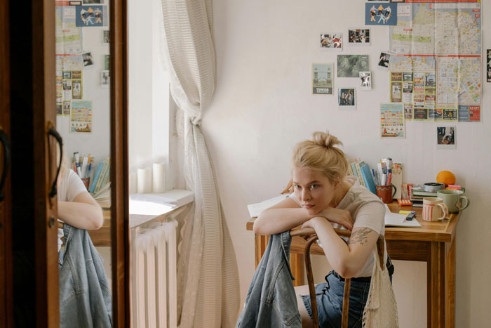 Young woman in a cozy room, contemplating, with photos and maps on the wall, capturing a mom-relationship-drama theme. Young woman in a cozy room, contemplating, with photos and maps on the wall, capturing a mom-relationship-drama theme.
