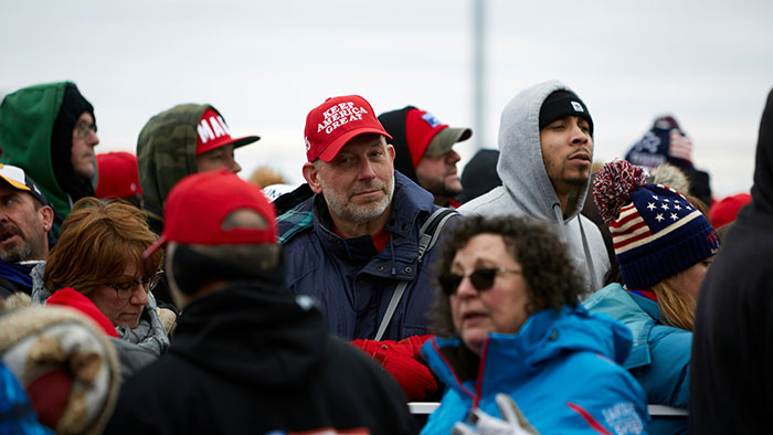 Crowd wearing winter clothing and red caps outdoors.