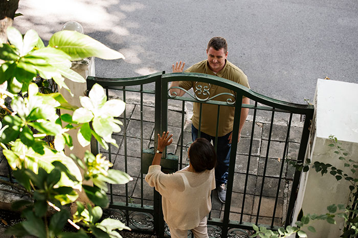 Person talking to a neighbor through a gate, highlighting a dispute over noise. Person talking to a neighbor through a gate, highlighting a dispute over noise.