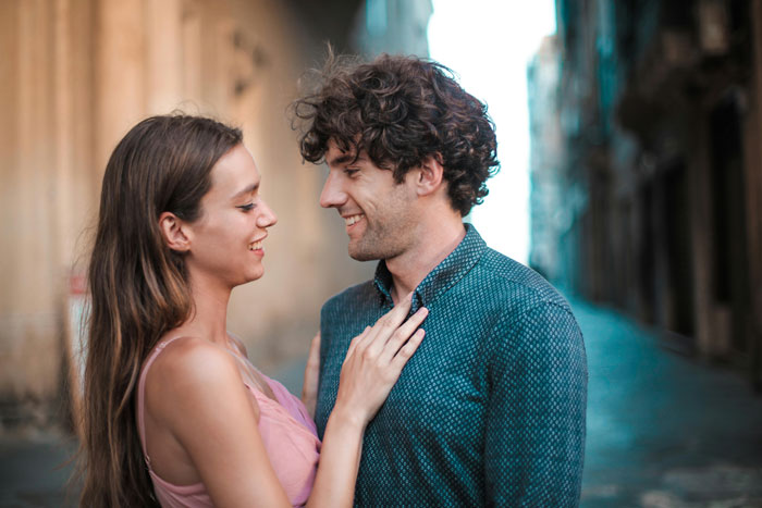 A couple smiling at each other in an alley, illustrating relationship dynamics in a neighbourhood affair context. A couple smiling at each other in an alley, illustrating relationship dynamics in a neighbourhood affair context.