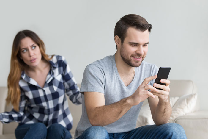 Dad using phone while partner looks concerned, highlighting child safety anxiety. Dad using phone while partner looks concerned, highlighting child safety anxiety.