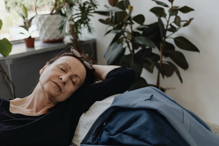 Older parent relaxing on a couch in a cozy room with plants in the background. Older parent relaxing on a couch in a cozy room with plants in the background.