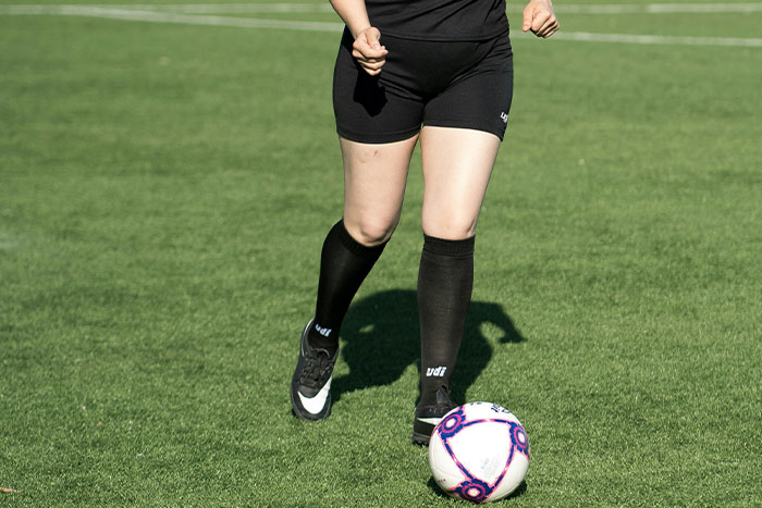 Girl playing soccer on grass field, wearing black shorts and socks, focusing on exercise. Girl playing soccer on grass field, wearing black shorts and socks, focusing on exercise.