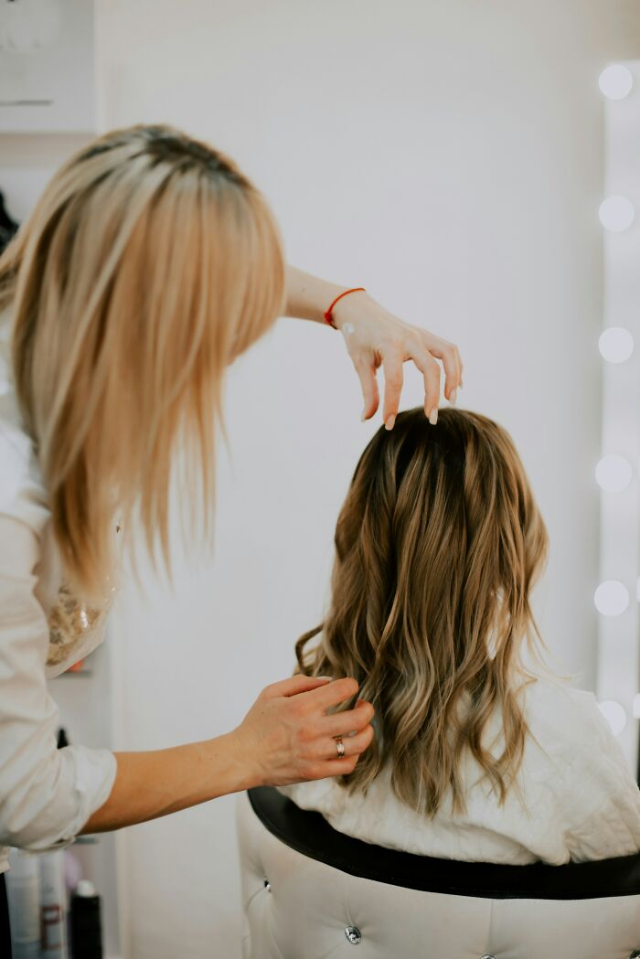 Hairstylist working on a client's hair in a salon, highlighting a cringe-worthy style moment.