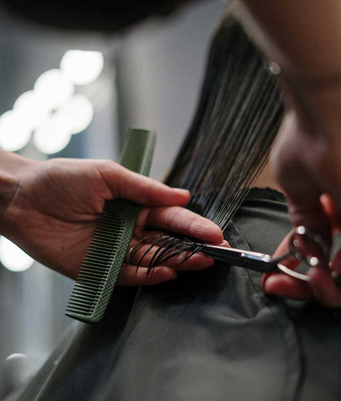Hairdresser creating inclusive cuts, using scissors and a comb. Hairdresser creating inclusive cuts, using scissors and a comb.