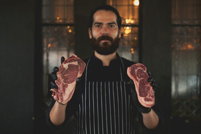 Butcher holding raw steaks.