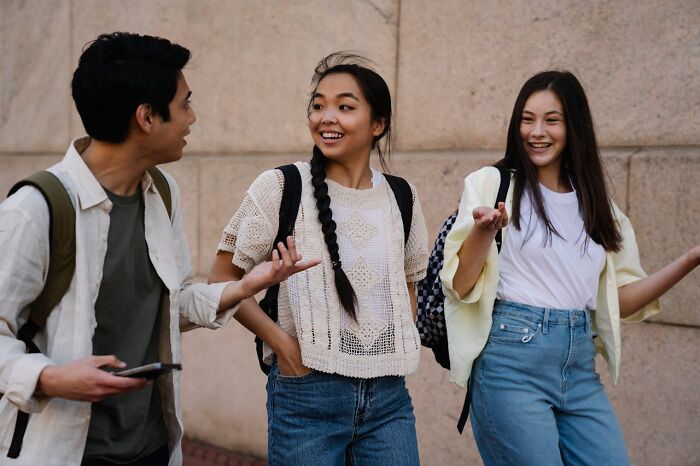 Three friends walking and talking, showcasing traits of truly good people with friendly, genuine smiles.